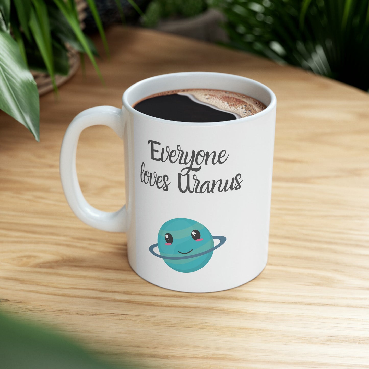 White Ceramic Mug with words in Script style black font that say, Everyone Loves Uranus. Beneath you find a Cute graphic of the Planet Uranus with an adorable face.  Check out the shop for more items at www.scorpiontees.etsy.com