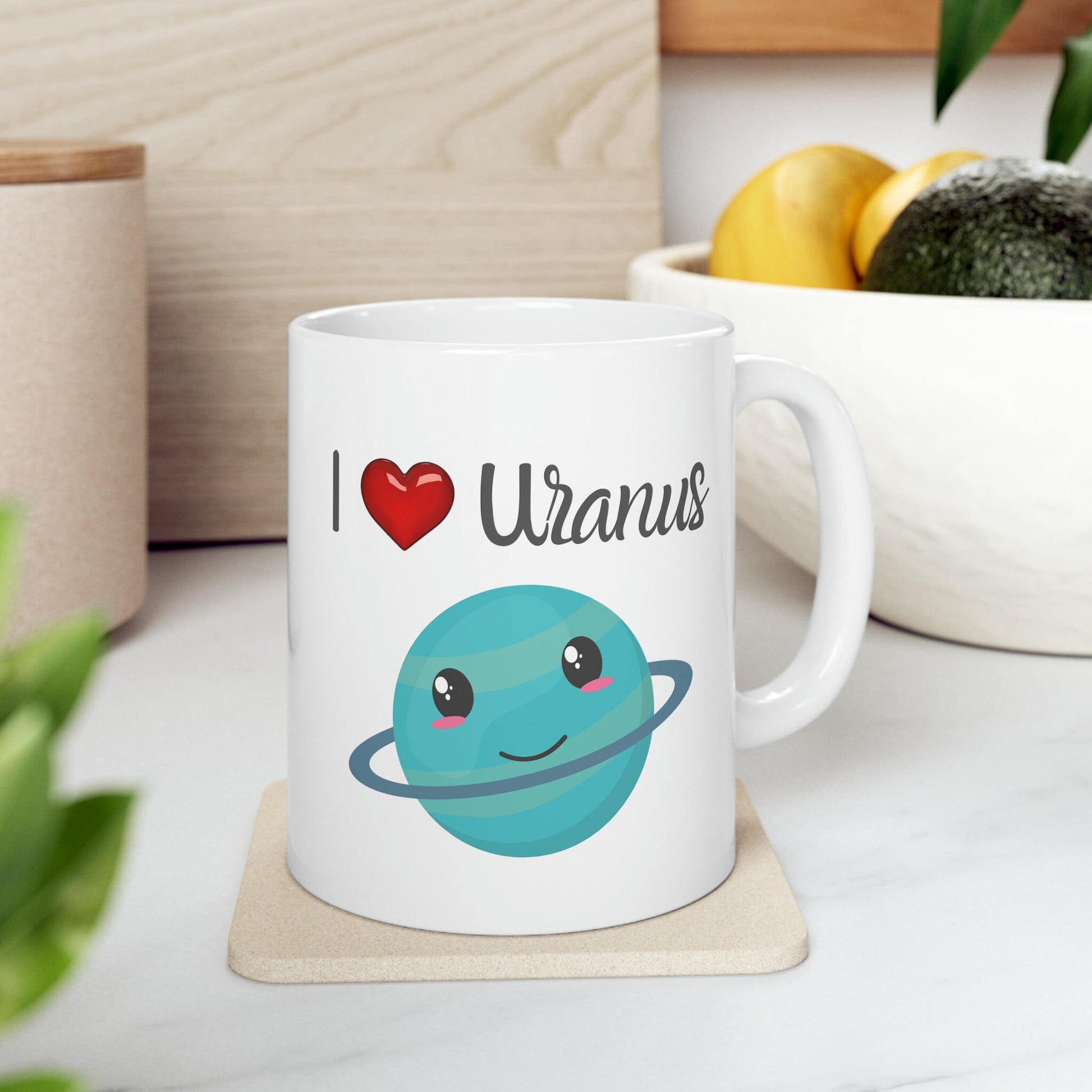 White Ceramic Mug with words in Script style black font that say, I Love Uranus.  Love as a red heart symbol.  Beneath you find a Cute graphic of the Planet Uranus with an adorable face.  Check out the shop for more items at www.scorpiontees.etsy.com