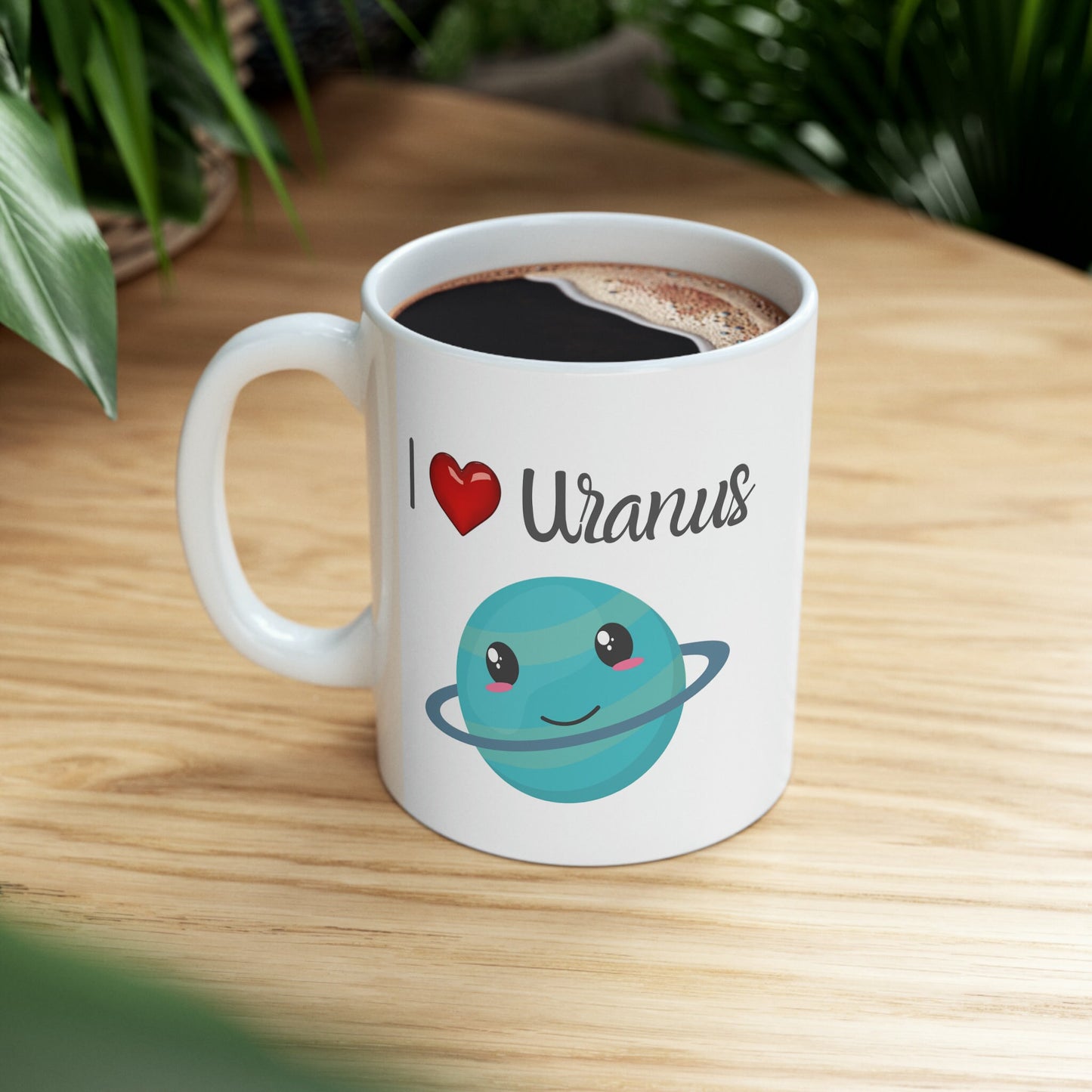 White Ceramic Mug with words in Script style black font that say, I Love Uranus.  Love as a red heart symbol.  Beneath you find a Cute graphic of the Planet Uranus with an adorable face.  Check out the shop for more items at www.scorpiontees.etsy.com