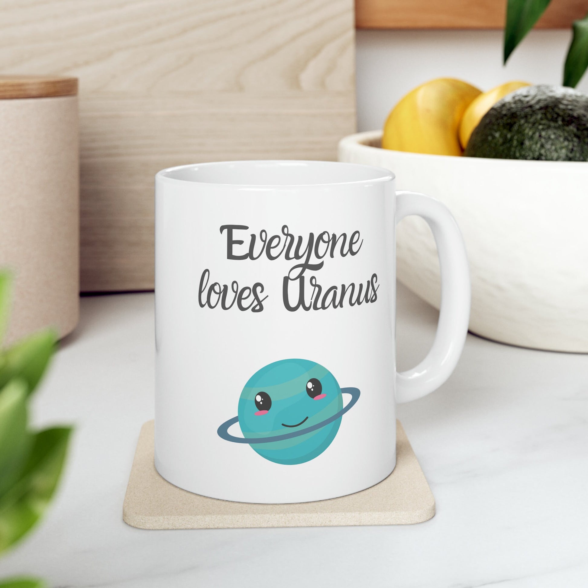 White Ceramic Mug with words in Script style black font that say, Everyone Loves Uranus. Beneath you find a Cute graphic of the Planet Uranus with an adorable face.  Check out the shop for more items at www.scorpiontees.etsy.com